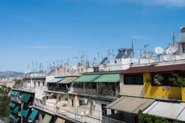 Atina, Yunanistan şehir manzarası. Tipik şehir mimarisi. Canlı binaların dışı. Teraslarda güneş panjurları. Güneşli bir yaz günü. Yeşil ağaçlar. Çatı destekli antenler.