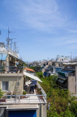 Atina, Yunanistan şehir manzarası. Tipik şehir mimarisi. Canlı binaların dışı. Teraslarda güneş panjurları. Güneşli bir yaz günü. Yeşil ağaçlar. Çatı destekli antenler.