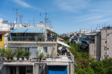 Atina, Yunanistan şehir manzarası. Tipik şehir mimarisi. Canlı binaların dışı. Teraslarda güneş panjurları. Güneşli bir yaz günü. Yeşil ağaçlar. Çatı destekli antenler.