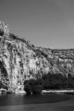 Vouliagmeni Gölü, Yunanistan 'da güneşli bir yaz gününde. Küçük tuzlu su gölü beslendi. Beyaz dağ manzarası ve yeşil su. Termal yay. SPA.