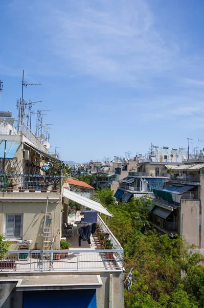 Atina, Yunanistan şehir manzarası. Tipik şehir mimarisi. Canlı binaların dışı. Teraslarda güneş panjurları. Güneşli bir yaz günü. Yeşil ağaçlar. Çatı destekli antenler.