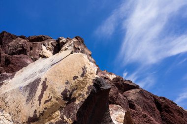 Santorini sahilinde büyük kırmızı ve sarı kayalık bir uçurum. Uzaylı manzarası.