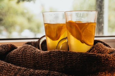 Limon ve portakallı yeşil çay ve bağışıklık sistemi olan birkaç bardak yakın plan. Örgü eşarp. Pencere pervazı. Soğuk havada sağlıklı sıcak içecek.