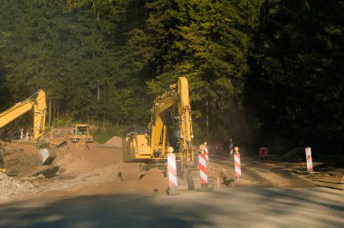 Yeni bir yol inşa etme süreci. Yol yapımı işe yarıyor. Sarı kazıcılar. Ağır makineler.