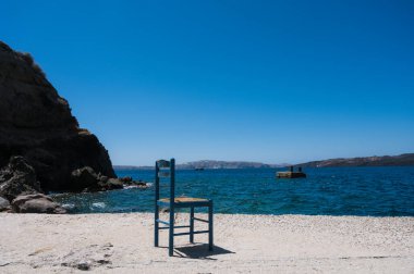 Santorini adasındaki eski Thira limanı. Denize yakın eski mavi ahşap sandalye. Kayalar ve deniz. Caldera görünümü.