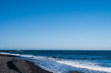 Santorini 'deki boş siyah kumsal manzarası. Ege Denizi 'nde dalgalar. Mavi gökyüzü. Yunanistan 'da eşsiz güzellikte bir doğa.