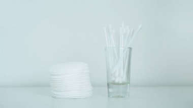 Cam bardaktaki pamuk ve pamuk bezlerini yakından çek. Beyaz arkaplan.