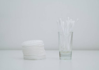 Cam bardaktaki pamuk ve pamuk bezlerini yakından çek. Beyaz arkaplan.