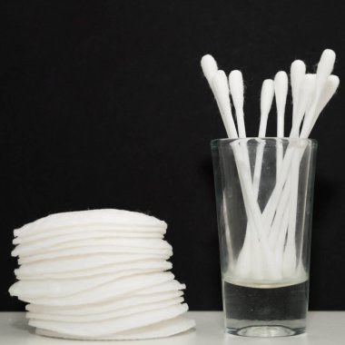 Cam bardaktaki pamuk ve pamuk bezlerini yakından çek. Siyah arkaplan.