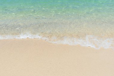 Güzel, berrak kumsal ve tropikal açık mavi deniz. Kumlu sahilde yumuşak bir mavi okyanus dalgası. Solgun su, berrak su. Deniz kenarında.