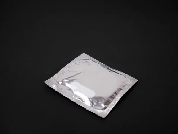 黒の背景にグレーのコンドームパッケージ パッケージプラスチック — ストック写真