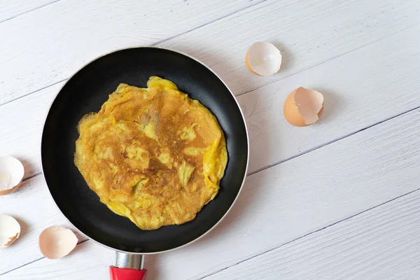 Üst manzara Tayland omleti mi yoksa küçük kızarmış yumurta mı? Beyaz masadaki yumurta kabuğunun yanında. Tayland sokak yemeği. Geleneksel Tayland usulü yemek. Ev yapımı yemek. Nefis ev yapımı yemekler..