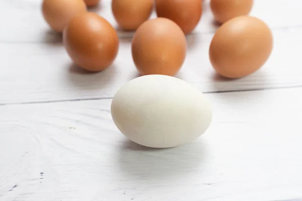 Ovo Branco Com Frente Muitos Ovos Mesa Branca Fundo Madeira — Fotografia de Stock