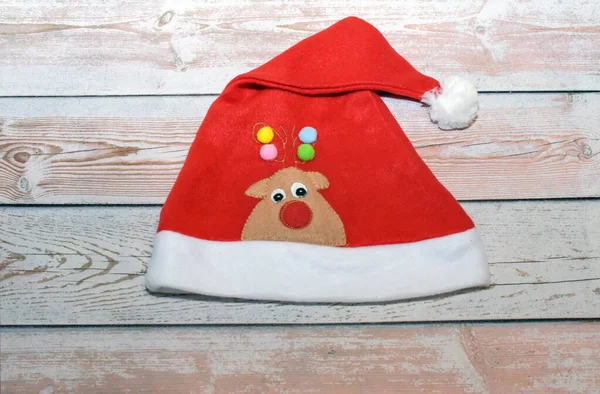 Masada geyik olan bir Noel şapkası. Noel 'i kutlamak için bir şapka. Yeni yılın ponponlu kırmızı şapkası. 1 Ocak 'taki kış tatili için karnaval şapkası..