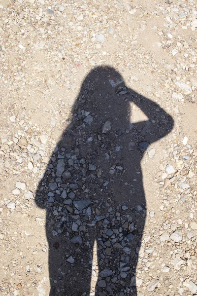 Het meisje nam een foto van haar schaduw op het zand. — Stockfoto