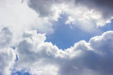 Mavi gökyüzünde beyaz bulutlar. Güneş ışınları bulutların arasından yol alır..