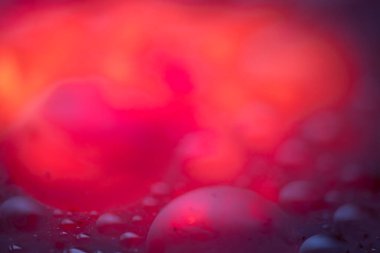 Islak, parlak, soyut bir arkaplan. Mavi, mor ve ateş rengi..