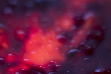 Islak, parlak, soyut bir arkaplan. Mavi, mor ve ateş rengi..