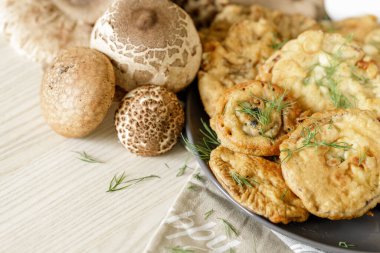 Bol yağda kızartılmış mantar şemsiyesi ve ahşap masa üzerinde yumurta.