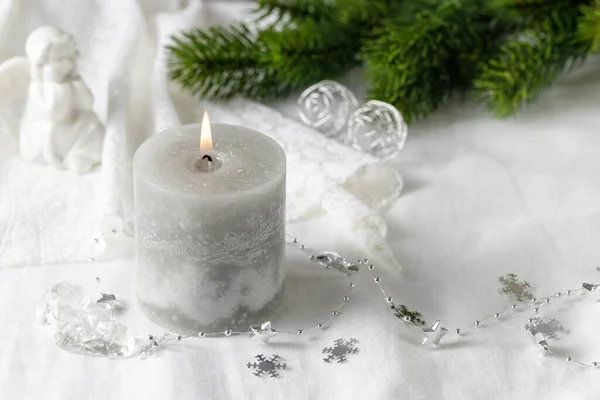 コピースペースと白いリネンのテキスタイルの背景に燃えるグレーのキャンドル モミの枝と天使像とクリスマスヴィンテージの装飾 — ストック写真