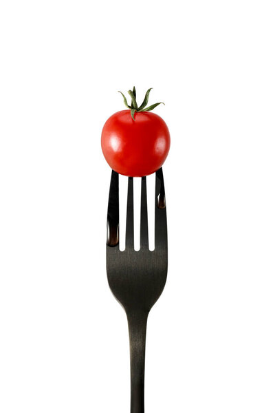 Fresh red cherry tomato on black fork isolated on white background
