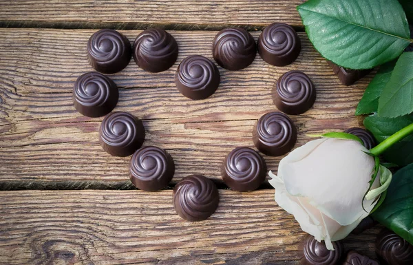 Cioccolatini e fiori su un tavolo di legno — Foto Stock
