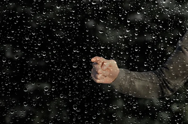 Hand behind a wet window — Stock Photo, Image