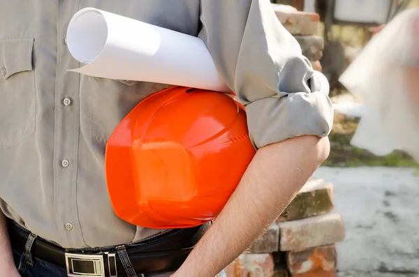 Homme tient un casque de construction de protection et le projet en h — Photo