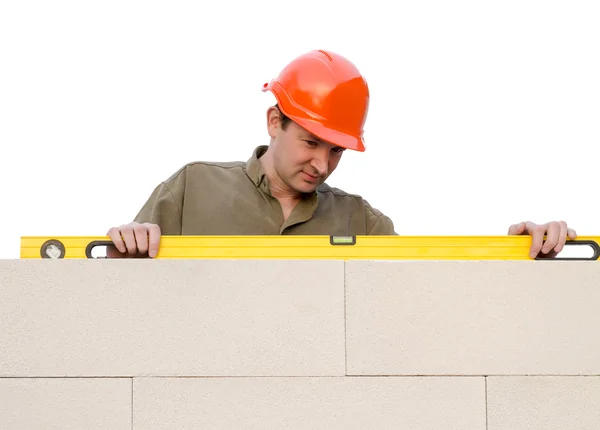 Builder checks a level of a brick wall — Stock Photo, Image