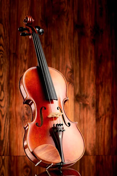 Close up of a violin on glass surface and wooden background — Stock Photo, Image