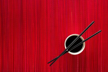 Yemek çubukları ve bambu hasır üzerinde soya sosu ile kase