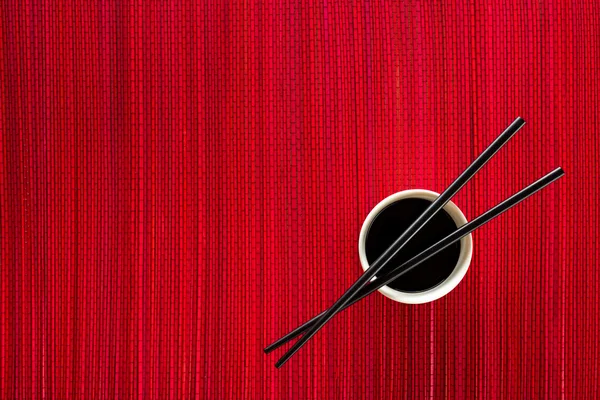 Chopsticks e tigela com molho de soja na esteira de bambu — Fotografia de Stock