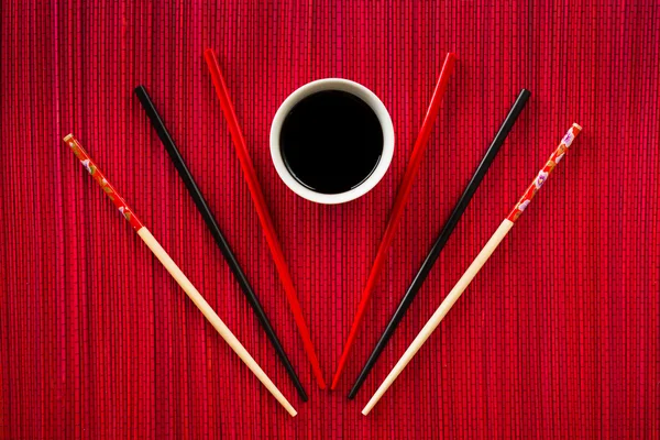 Chopsticks e tigela com molho de soja na esteira de bambu — Fotografia de Stock