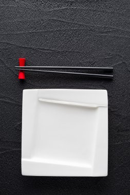 Yemek çubukları ve beyaz plaka üzerinde siyah kaya