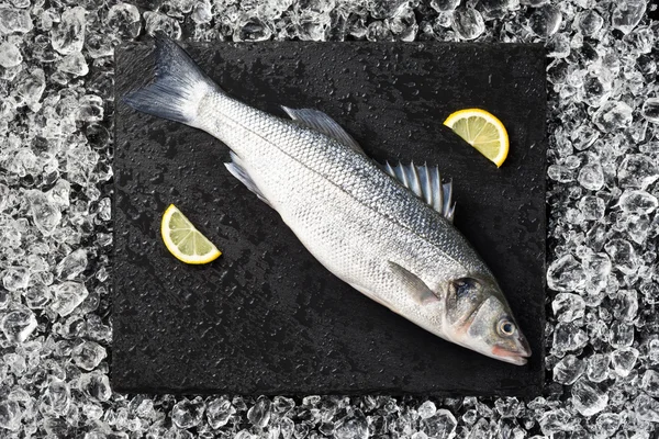 Pescado fresco sobre hielo sobre una mesa de piedra negra vista superior — Foto de Stock