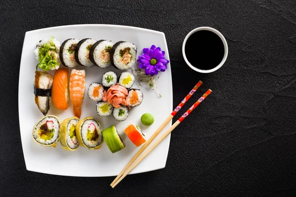 Sushi em placa branca em uma mesa de pedra preta — Fotografia de Stock