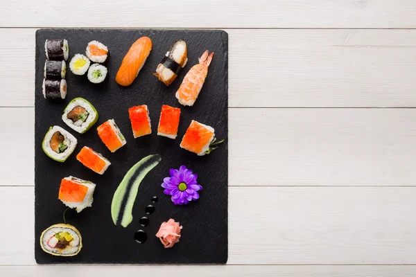 Sushi sur plaque de pierre noire sur une table en bois vue du dessus — Photo