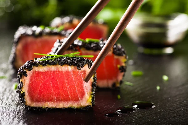 Жареный стейк из тунца в черном кунжуте с палочками для еды — стоковое фото