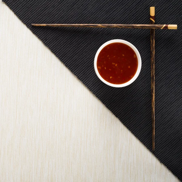 Chopsticks and bowl with sauce on table mat top view — Stock Photo, Image