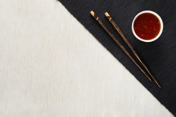 Chopsticks and bowl with sauce on table mat top view — Stock Photo, Image