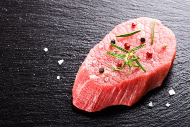 Raw fresh beef steak on dark stone background closeup clipart