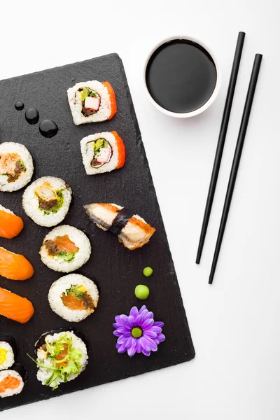 Sushi, ätpinnar och soja på svart sten skylt ovanifrån — Stockfoto