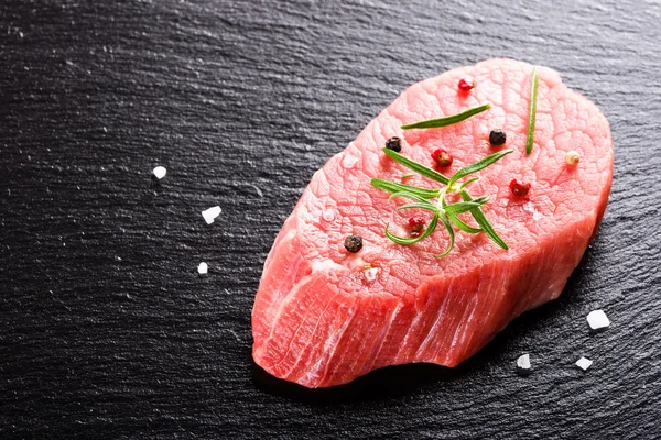Čerstvé hovězí steak na tmavém pozadí kamene closeup — Stock fotografie