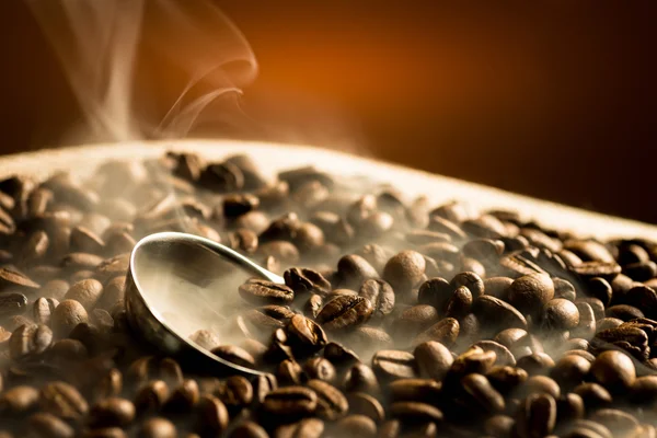 Roasting coffee beans with smoke on dark background — Stock Photo, Image
