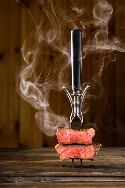 Sliced beef steak on a fork on the wooden table — Stock Photo, Image