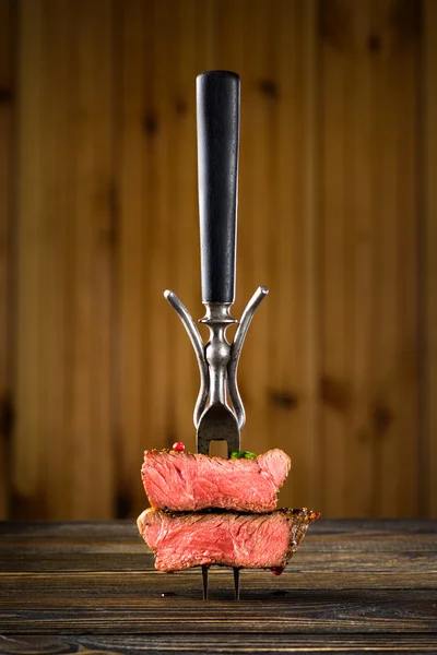 Bife de vaca fatiado em um garfo na mesa de madeira — Fotografia de Stock