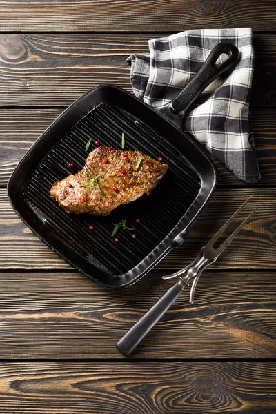 Steak de boeuf sur poêle à griller sur une table en bois vue sur le dessus — Photo