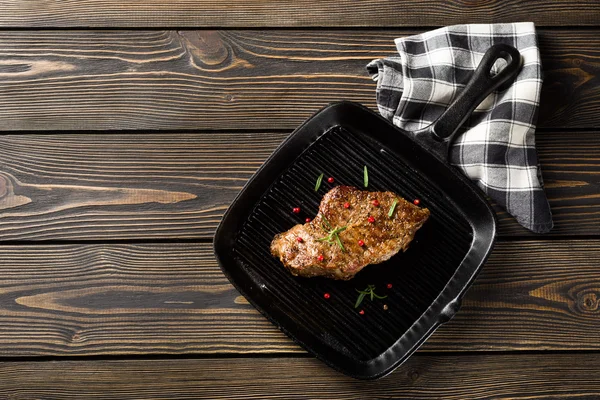 Hovězí steak na gril pánev na dřevěný stůl horní pohled — Stock fotografie