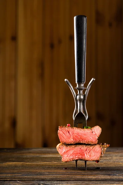 Sliced beef steak on a fork on the wooden table — Stock Photo, Image