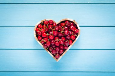 kiraz mavi ahşap masa üstü bir kalp kutusunda görüntülemek